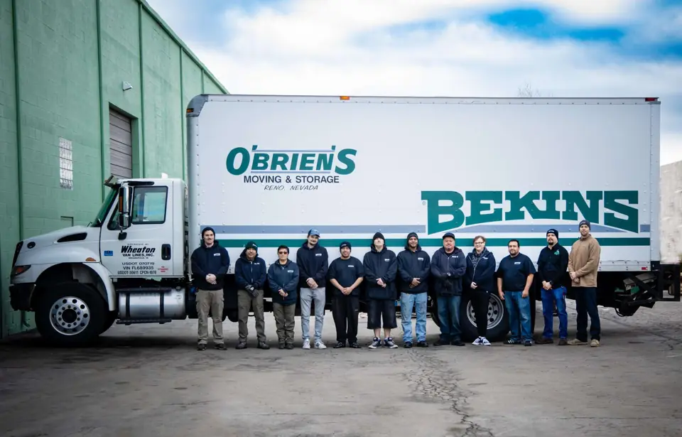 The O'Brien's team lined up beside a white O'Brien's and Bekins straight truck at the warehouse