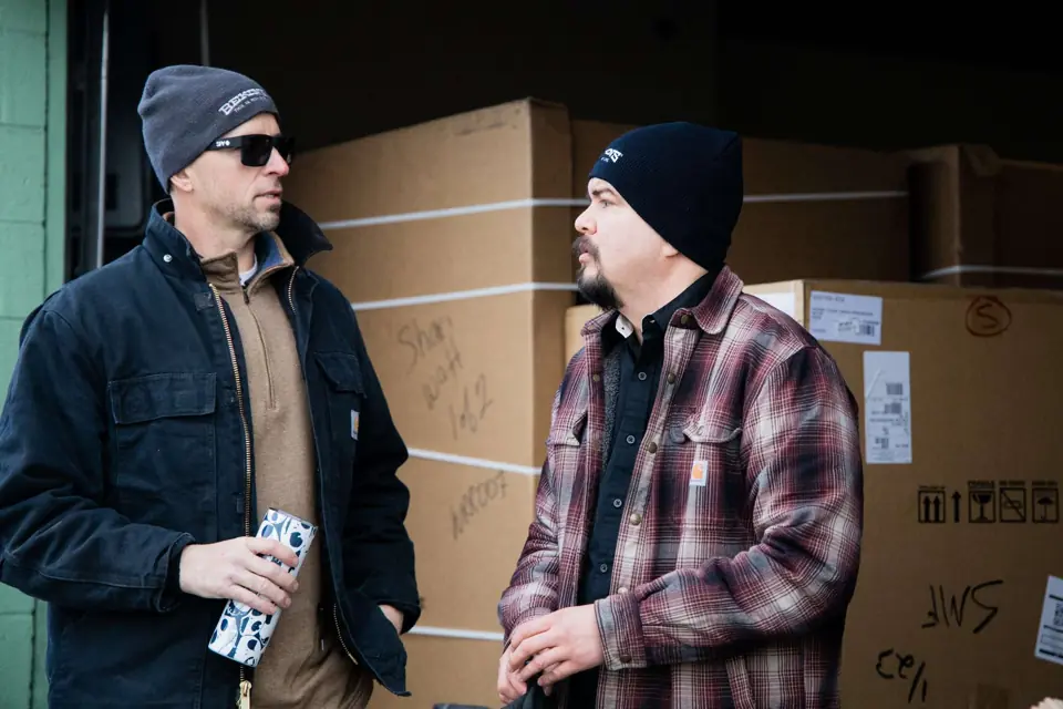 Two O'Brien's crew members talking beside stacked cartons at the warehouse
