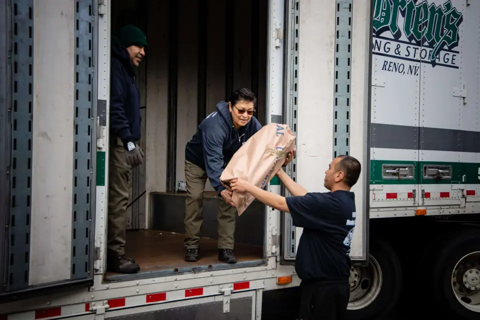 O'Brien's movers passing a wrapped item down from the trailer