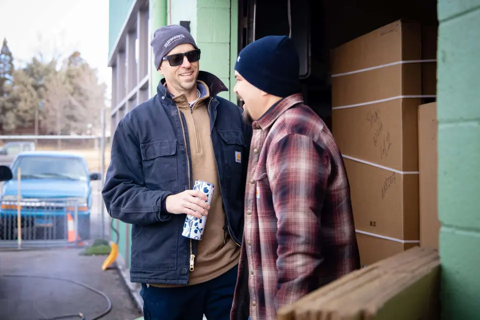 Two O'Brien's crew members sharing a laugh at the warehouse door
