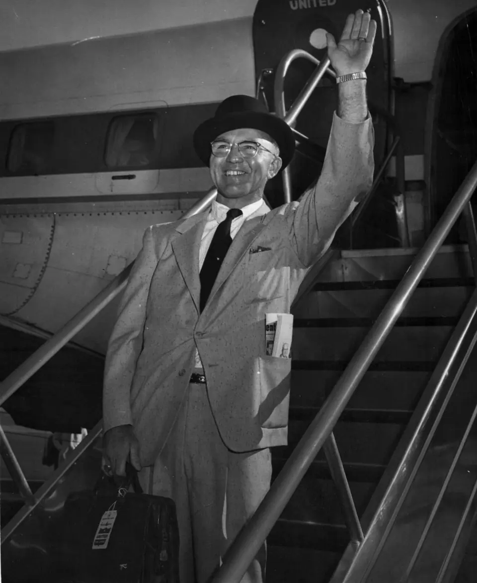 Our founder Harry O'Brien waving from the stairs of an airliner, a black-and-white photo