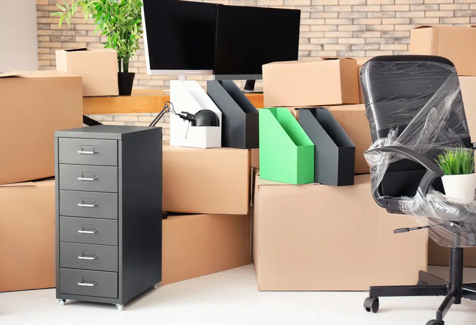 Cardboard boxes, a filing cabinet and a plastic-wrapped office chair ready for an office move