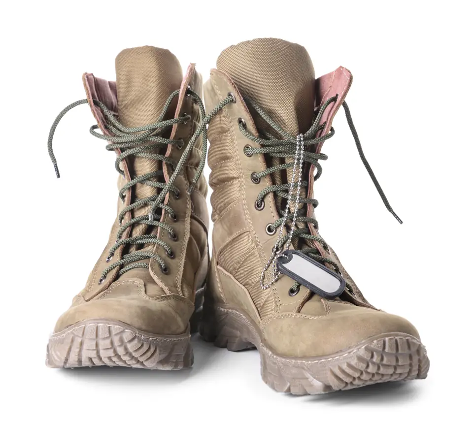 Pair of tan military boots with a dog tag on a white background
