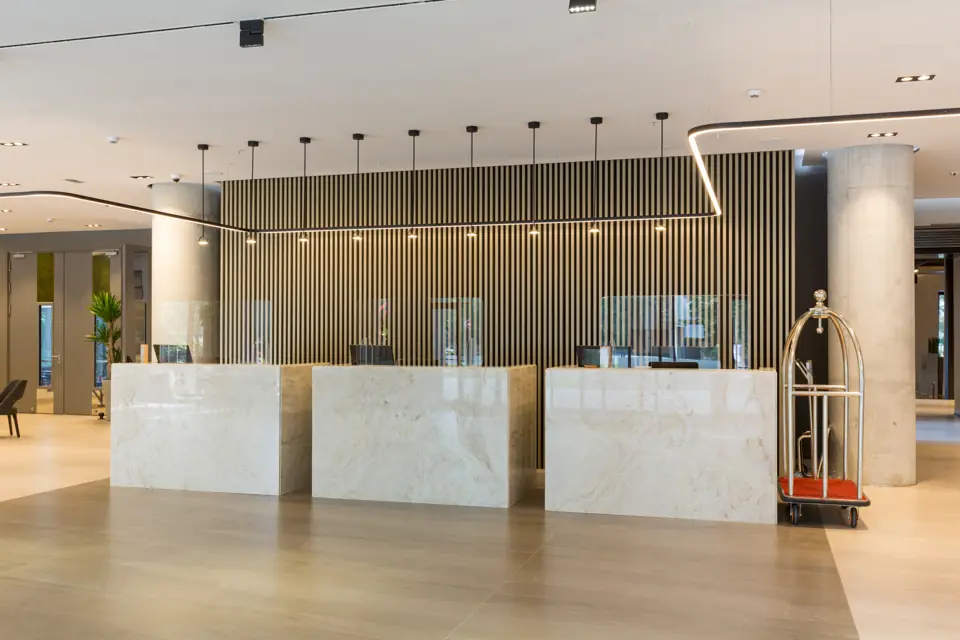 Empty hotel lobby with marble reception desks and a luggage cart
