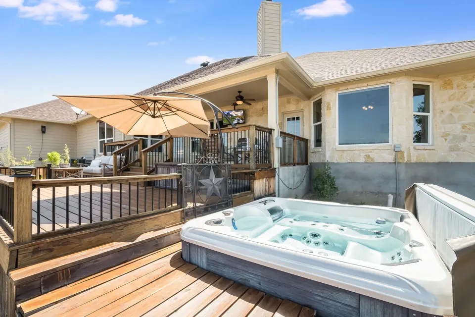 Hot tub on a wooden backyard deck beside a house, no people