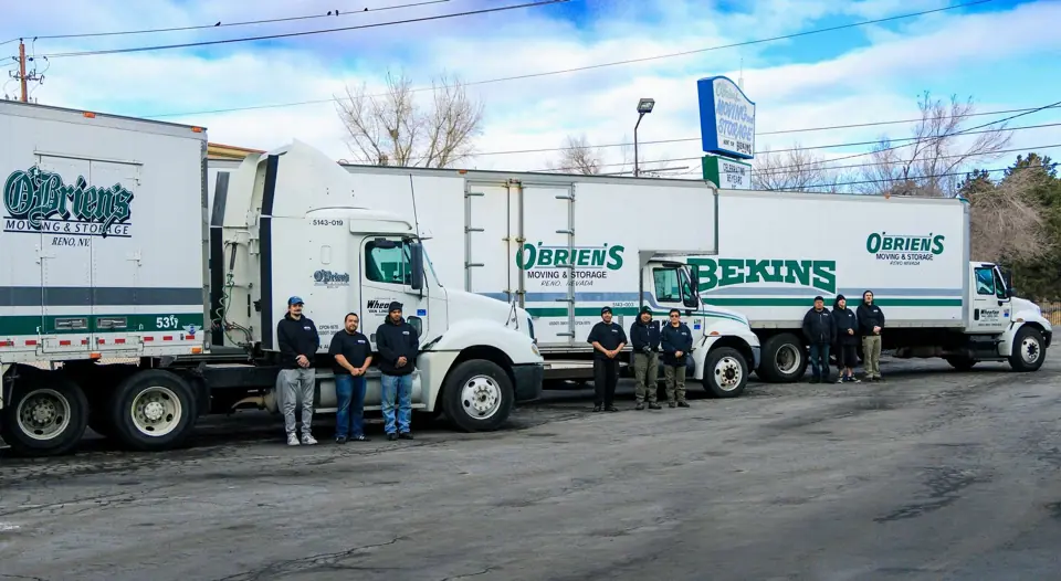 O'Brien's and Bekins trucks parked in a row in the yard with crew members beside them