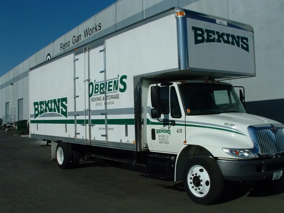 An O'Brien's and Bekins straight truck parked outside a warehouse