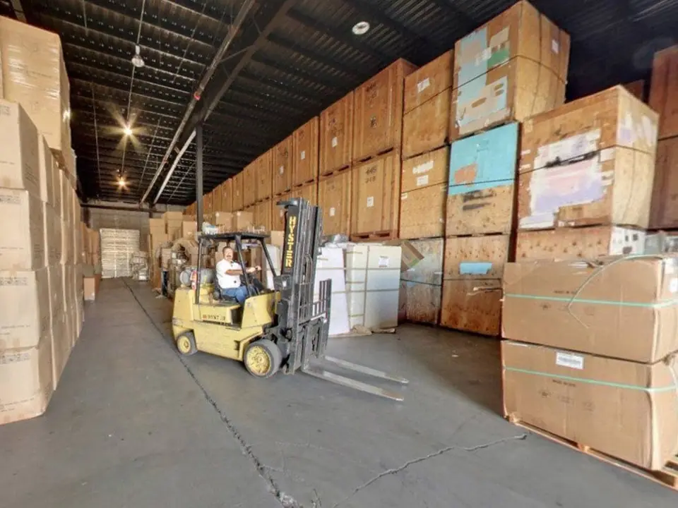 A forklift moving through aisles of wooden storage vaults in the O'Brien's warehouse